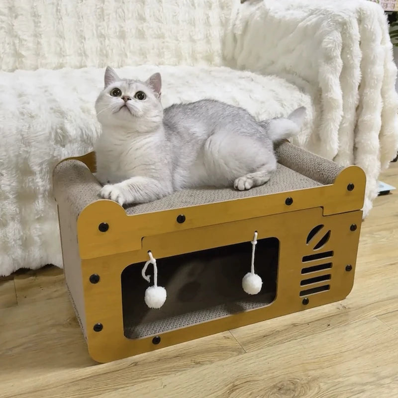 Un chat gris et duveteux est assis dans une maison pour chat beige avec un panneau de scratch intégré.
