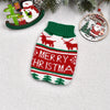 A knitted red and green Christmas sweater featuring reindeer and Merry Christmas patterns, displayed with holiday greenery.