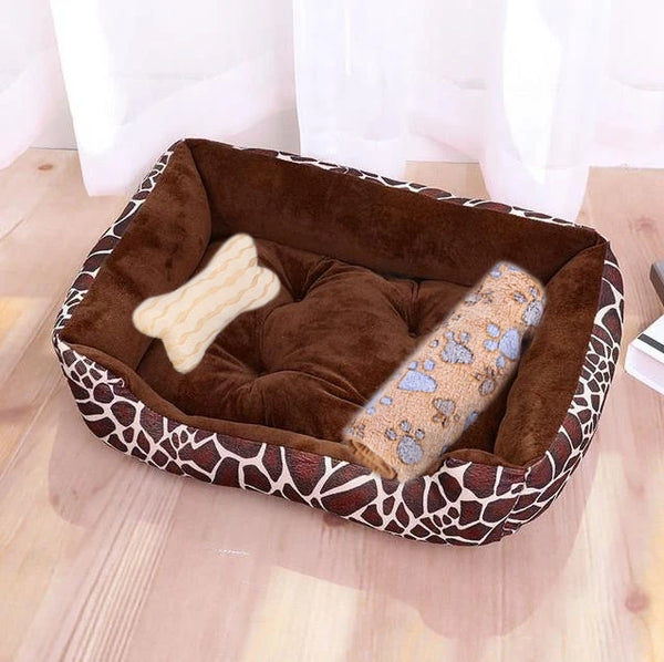 A brown faux leather dog bed with a patterned rim and a cream-colored bone shaped insert is shown on a wooden floor.