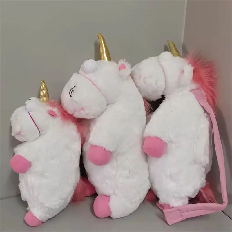 A set of three white unicorn plush dolls with pink accents and gold horns, displayed against a light gray background.