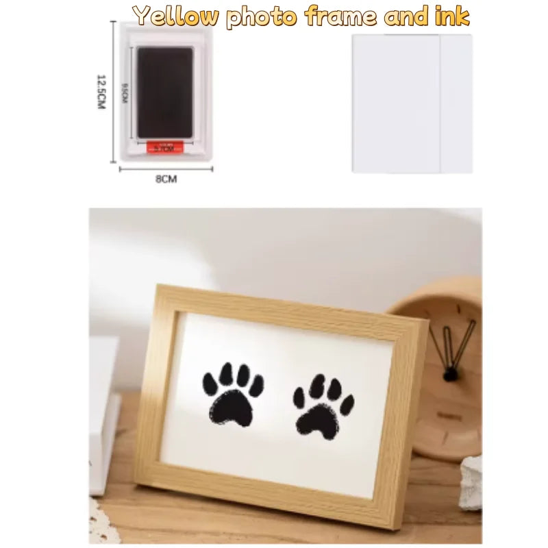 Gerahmtes gelbes Foto mit einem Tintenpad und einem schwarzen Pfotenspuren-Motiv auf weißem Papier.