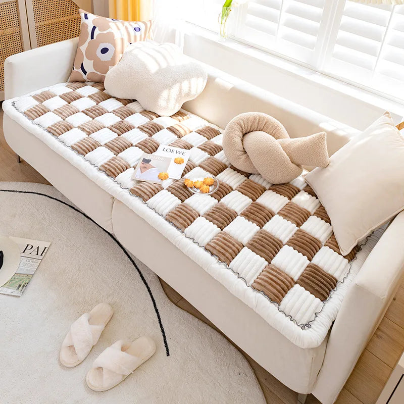 A beige plush fleece pet bed mat with a checkered pattern is placed on a white sofa.