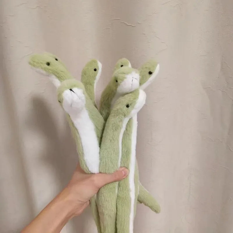A hand is holding a plush toy of a green snake with white markings against a light background.