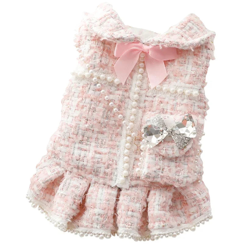 Une robe pour animal de compagnie rose texturée avec bordure de perles blanches et un nœud rose.