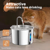 A ginger cat is drinking water from a stainless steel cat water fountain with a faucet design.