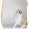 A fluffy gray and white cat is interacting with a pink silicone mouse tail toy.