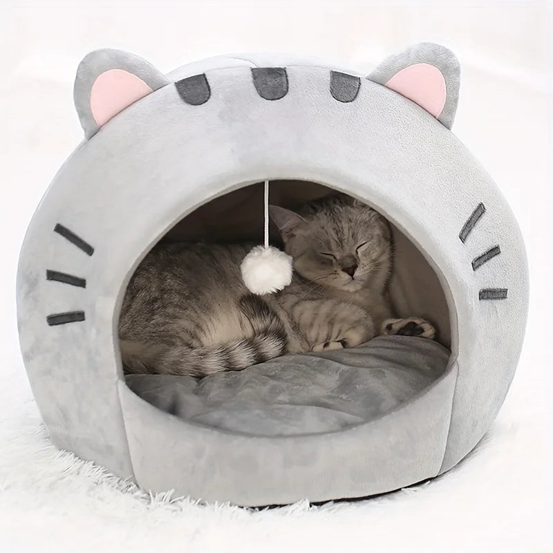 A gray plush cartoon cat cave bed with pink ears and facial markings, featuring a cozy interior for a small pet.