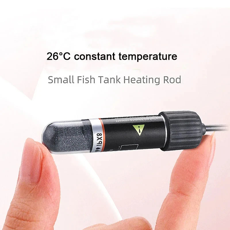 A hand holds a small black fish tank heating rod with an IX8 unit, designed for a constant 26°C temperature.