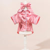 Rosa Satin-Hundpyjama-Set mit passender Schleife und Haarband auf einem Mannequin.