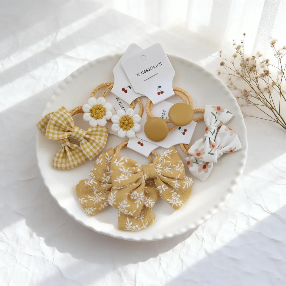 Collection de nœuds élastiques pour cheveux en fibres naturelles, avec tissus floraux et à motifs sur une assiette blanche.