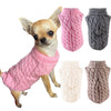 Un chihuahua portant un pull tricoté rose et plusieurs mitaines pour chiens tricotées gris et roses.