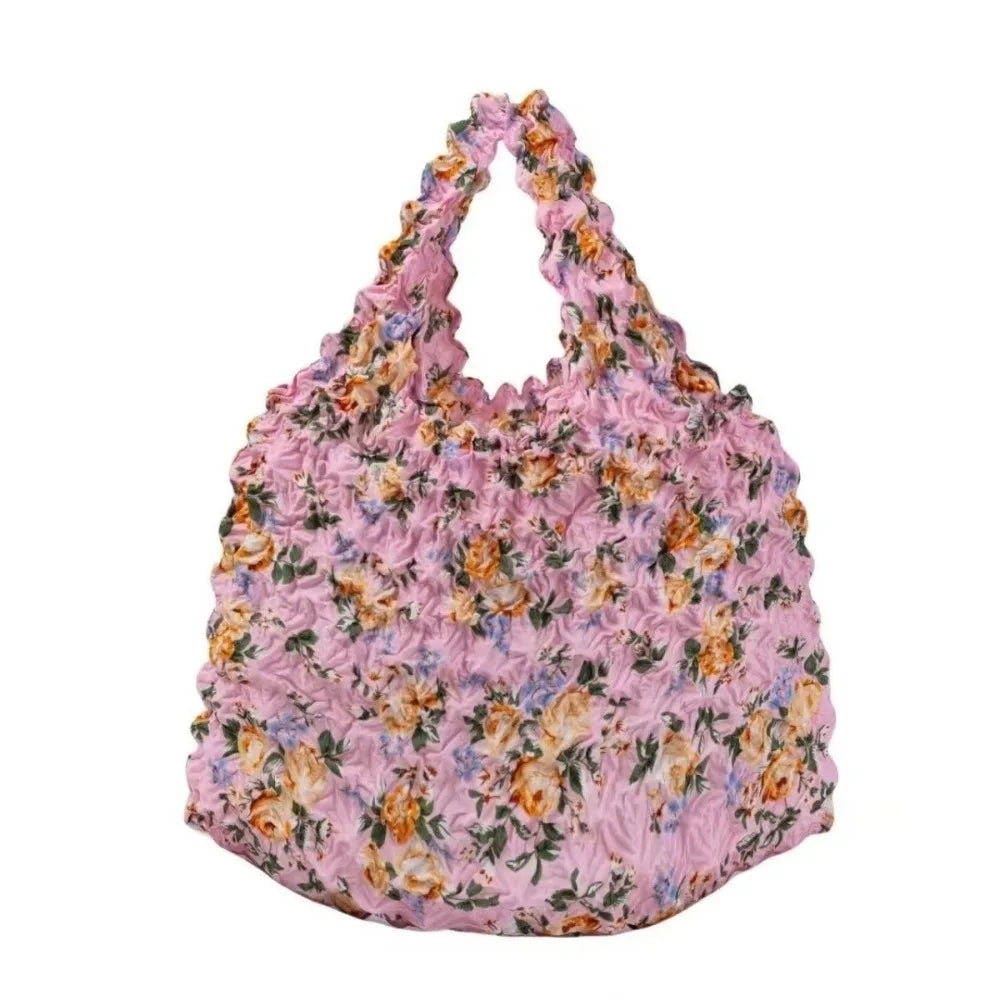 A pink floral fabric tote bag with a ruffled edge and scattered orange and purple flowers.