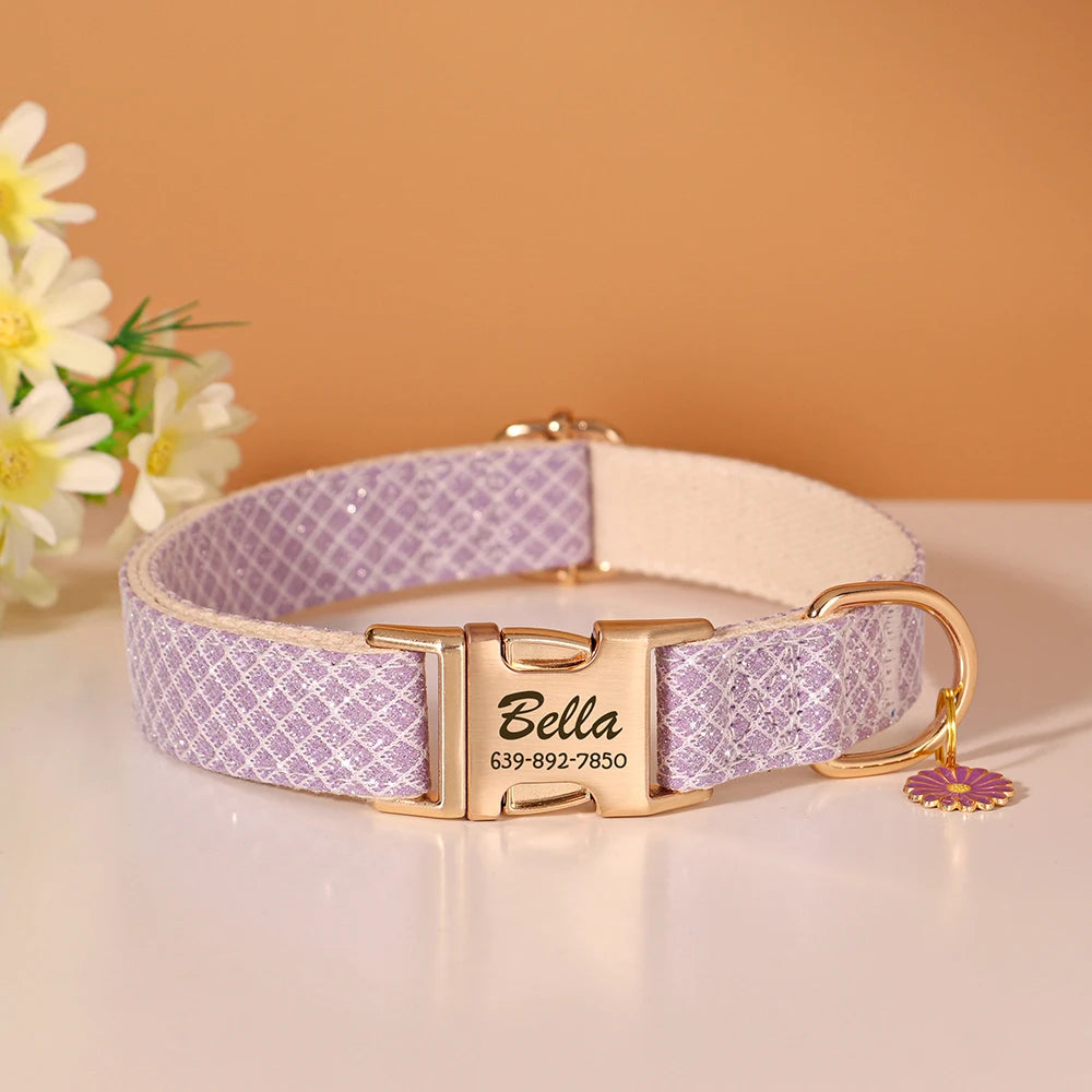 A lavender patterned nylon dog collar with a gold buckle and an engraved Bella name tag resting on a white surface.