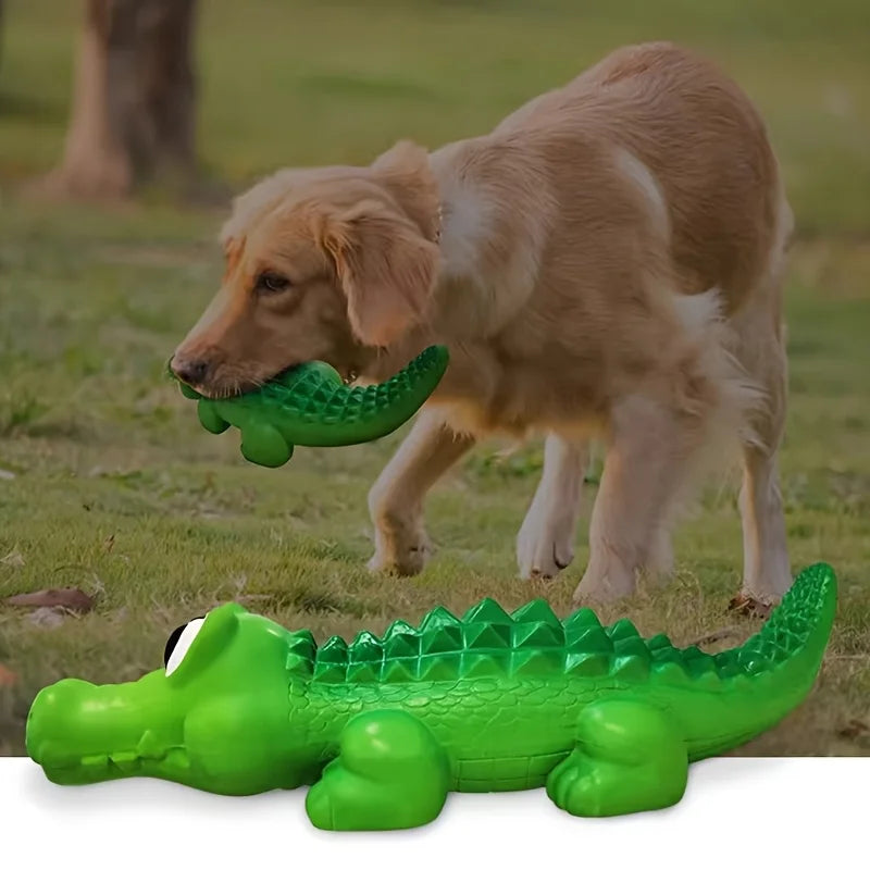 A light brown dog is interacting with a green crocodile-shaped latex chew toy.