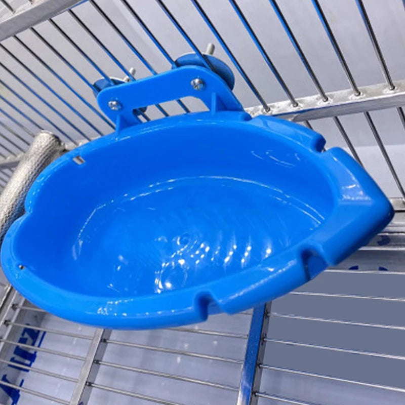 A bright blue multi-use parrot feeding and bathing tray is shown hanging in a metal rack.