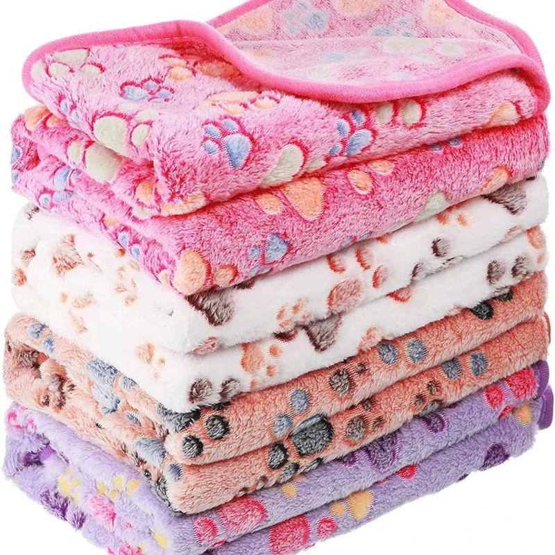 Stack of pink and white flannel fleece pet blankets with paw print designs