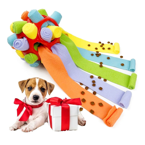 A colorful snuffle ball toy for dogs with various colored fabric strips and a small dog next to a gift box.