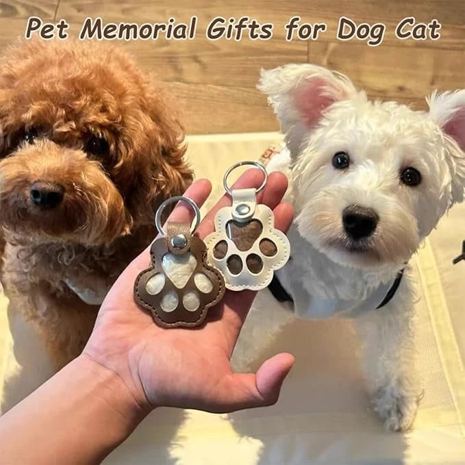 A hand holds a leather pet fur keepsake keychain charm next to a white dog.
