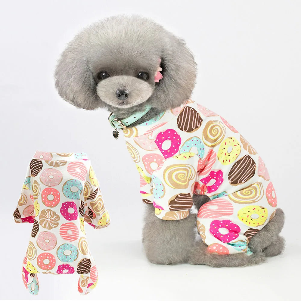 A fluffy gray dog wearing a patterned cotton pajama top with various colorful designs.