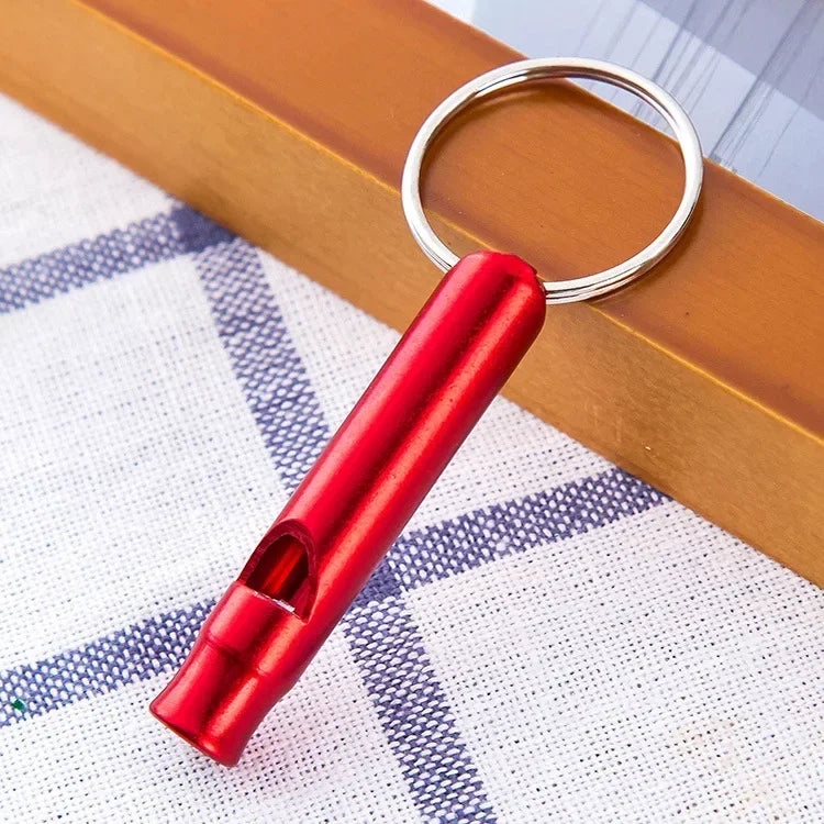 Rotes Edelstahl-Hundehalsbandpfeif mit silbernem Schlüsselring auf weißem Karomuster.