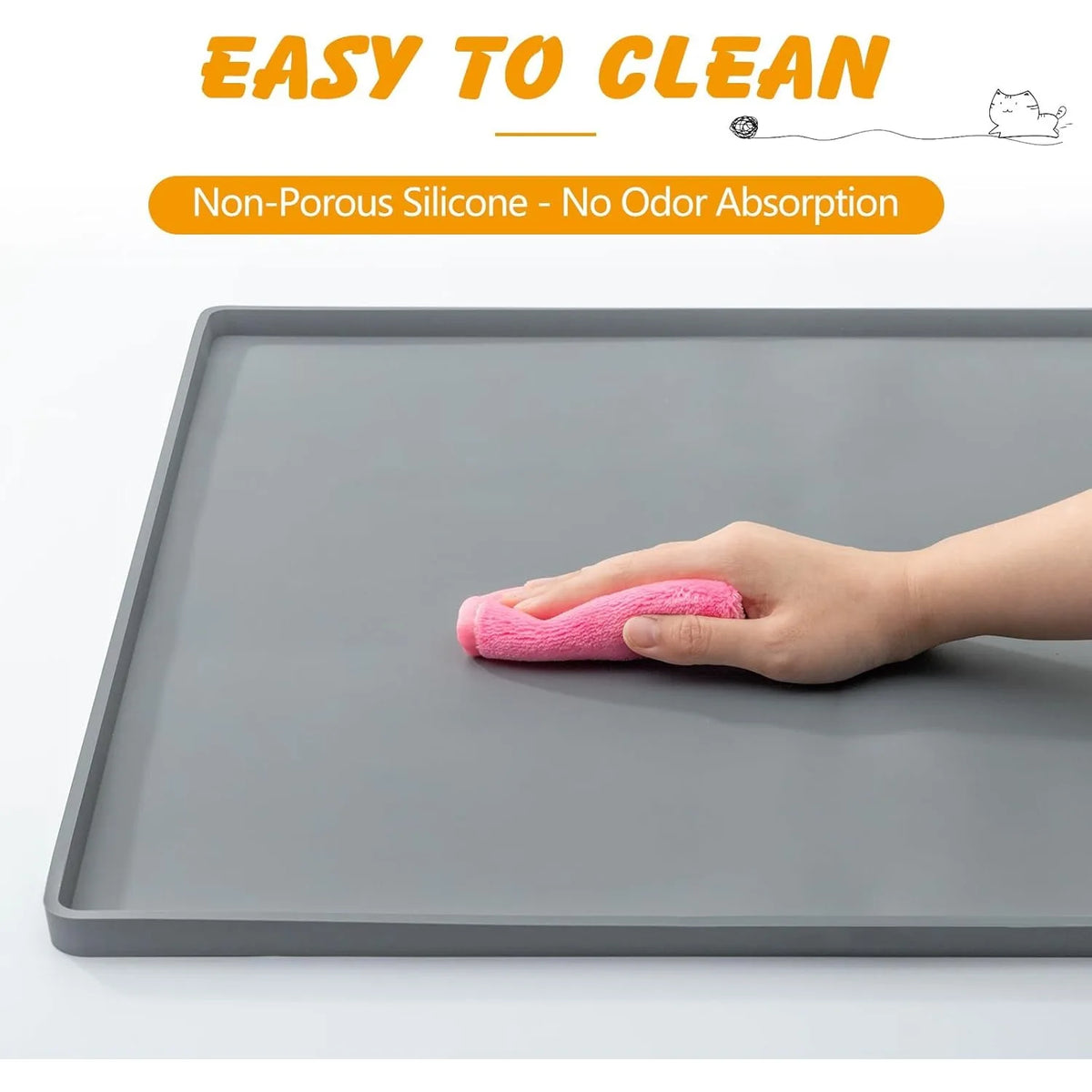 A hand is cleaning a gray silicone pet training mat with a pink sponge.