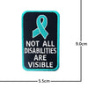 A black embroidered patch featuring a teal awareness ribbon and the text NOT ALL DISABILITIES ARE VISIBLE.