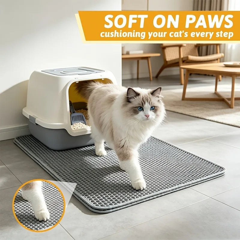 A fluffy white cat walks on a gray, textured litter mat placed in front of a white plastic litter box.