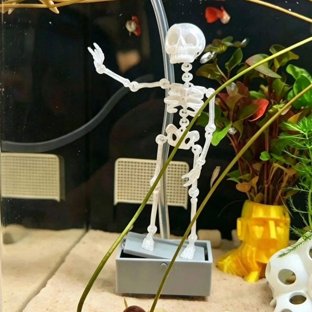 A white dancing skeleton figure is displayed in a clear aquarium setup with plants and sand.