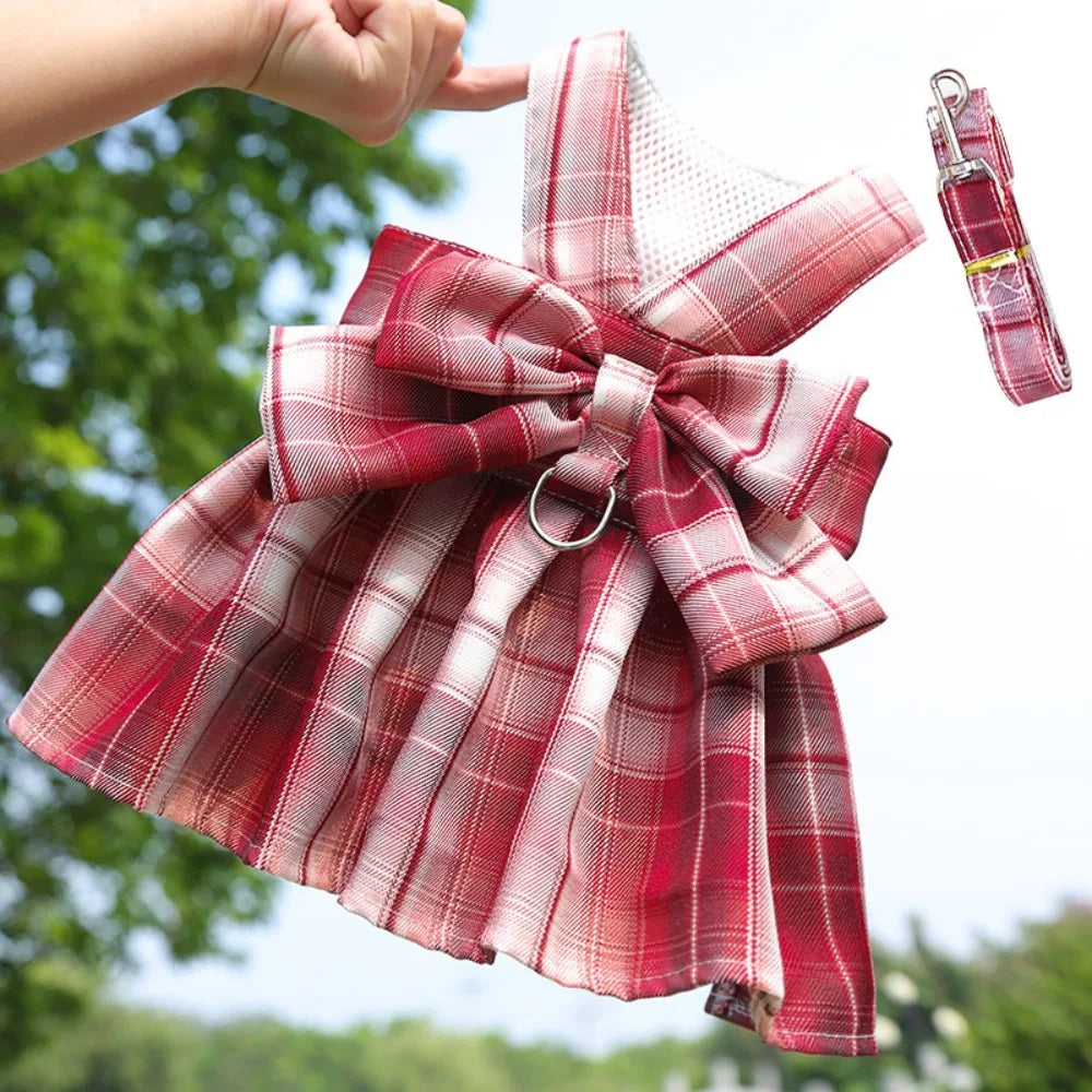 A red and white plaid reusable dog harness dress with a bow and attached leash.