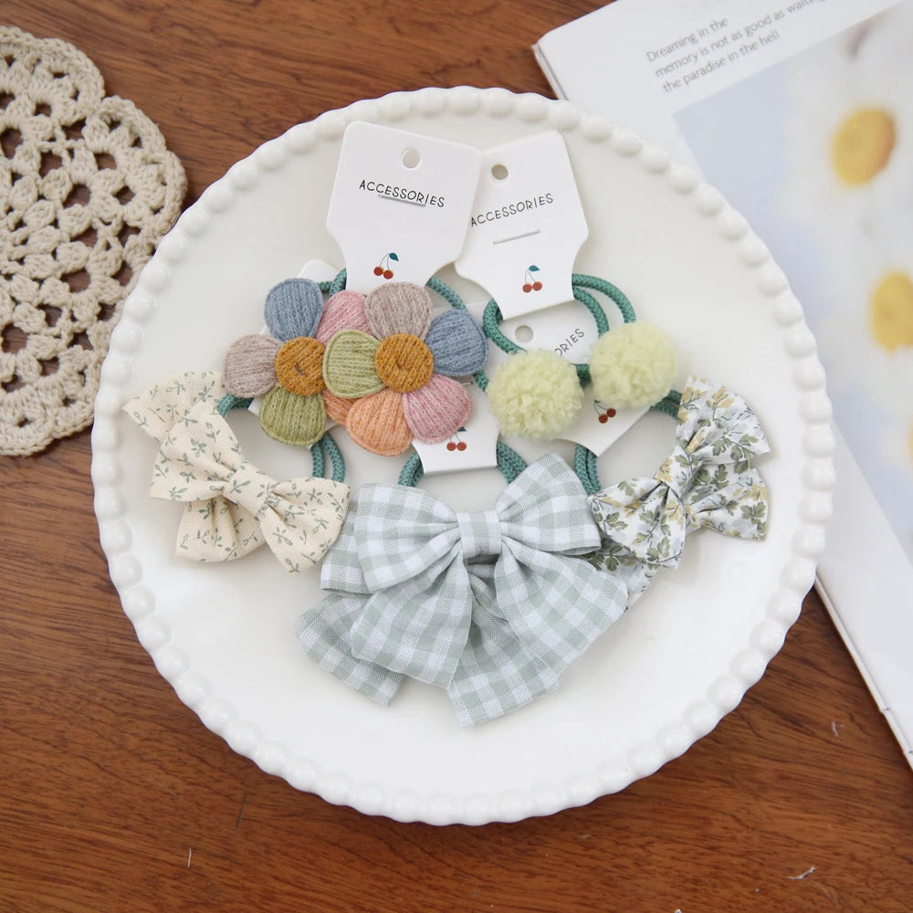 Collection de nœuds pour cheveux en tissu colorés et accessoires présentés sur une assiette blanche.