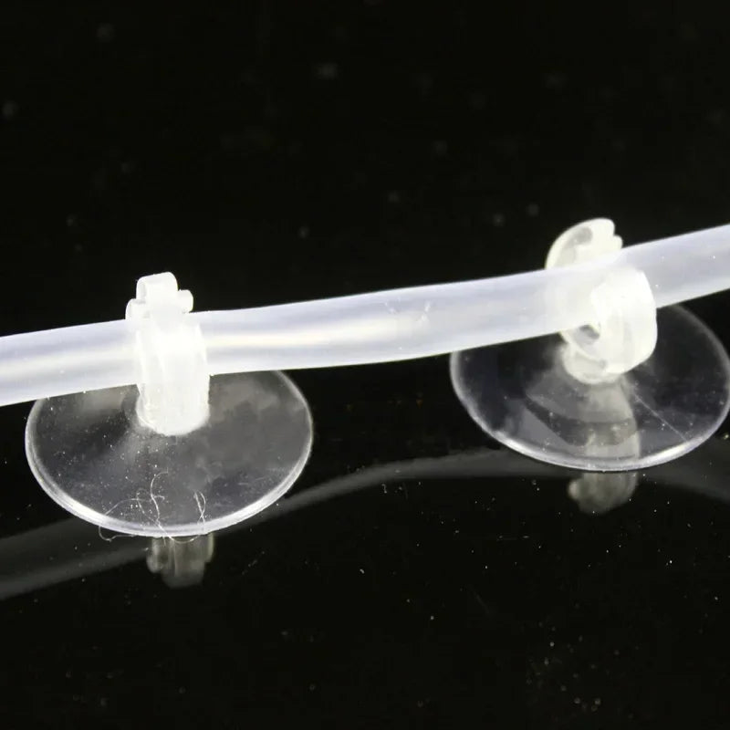 A clear plastic aquarium air line with suction cups is shown against a black background.