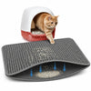 A fluffy orange cat is peering out of a white litter box, with a gray non-slip mat lying in front of it.
