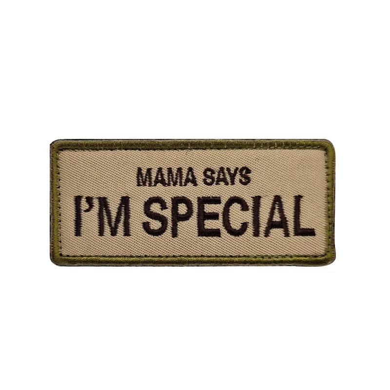 A rectangular tan mesh pet harness tag with black embroidered text that reads Mama Says I'm Special