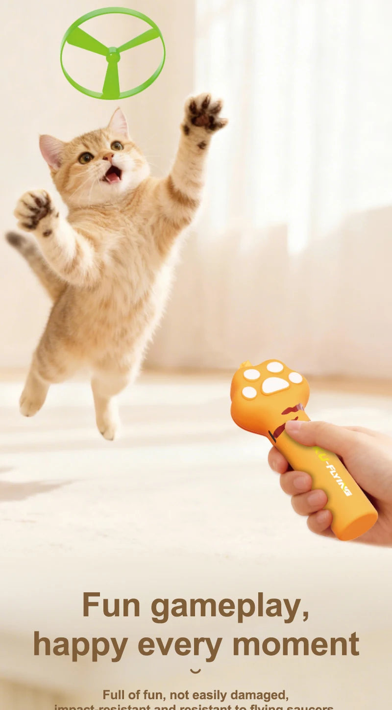 A kitten plays with an orange interactive cat wand toy featuring a flying saucer attachment.
