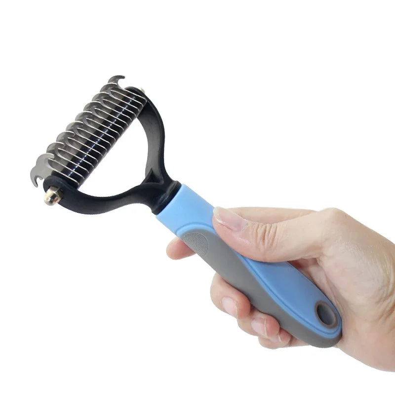 A hand holds a stainless steel pet hair removal comb brush with a blue handle, ready for grooming.