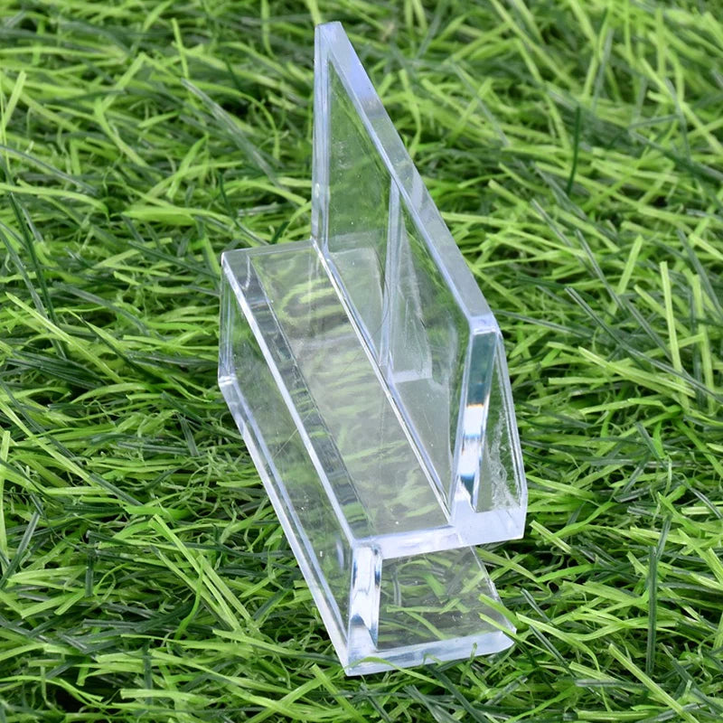 Klare Acrylglas-Deckelclips liegen auf grünem Gras.