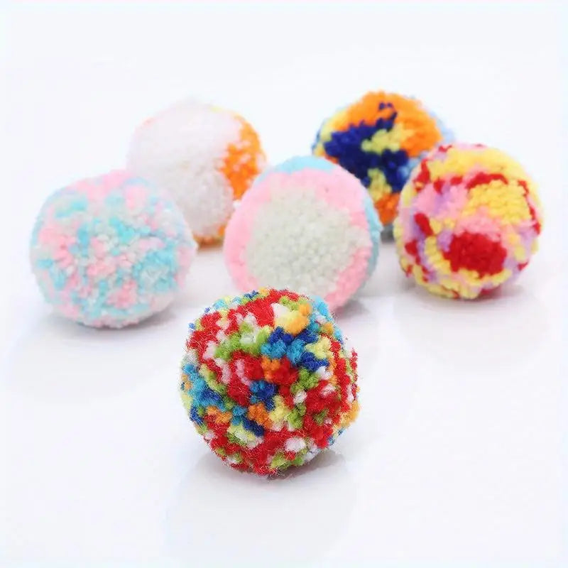 A collection of colorful plush wool balls in various shades including orange, yellow, pink, and blue.