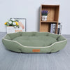 A light green luxurious corduroy pet sofa bed for dogs and cats resting on a gray surface.