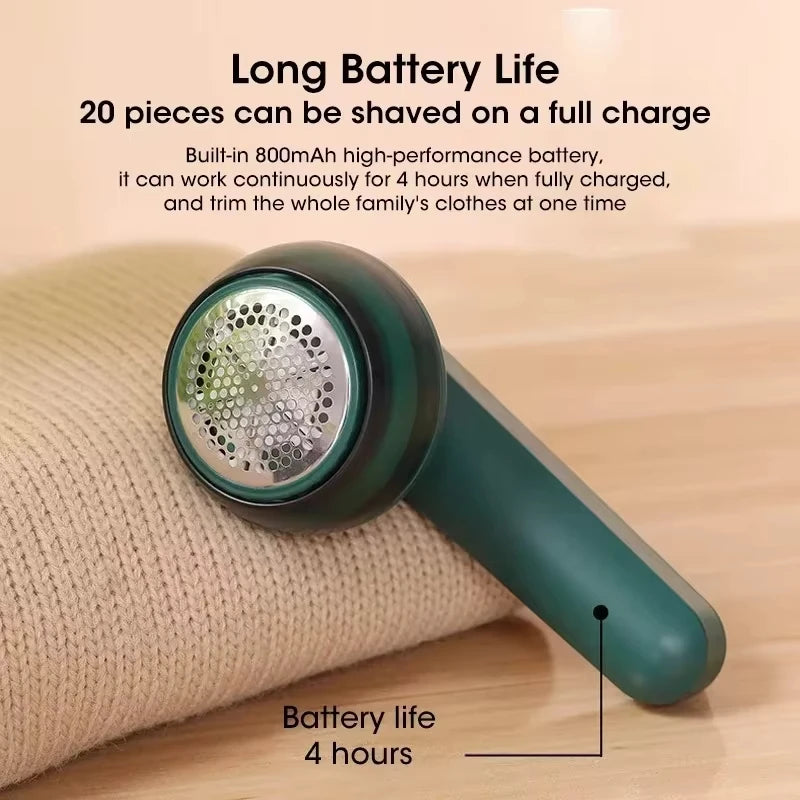 A close-up of a portable electric lint and fabric shaver in a dark green color resting on a beige cloth.