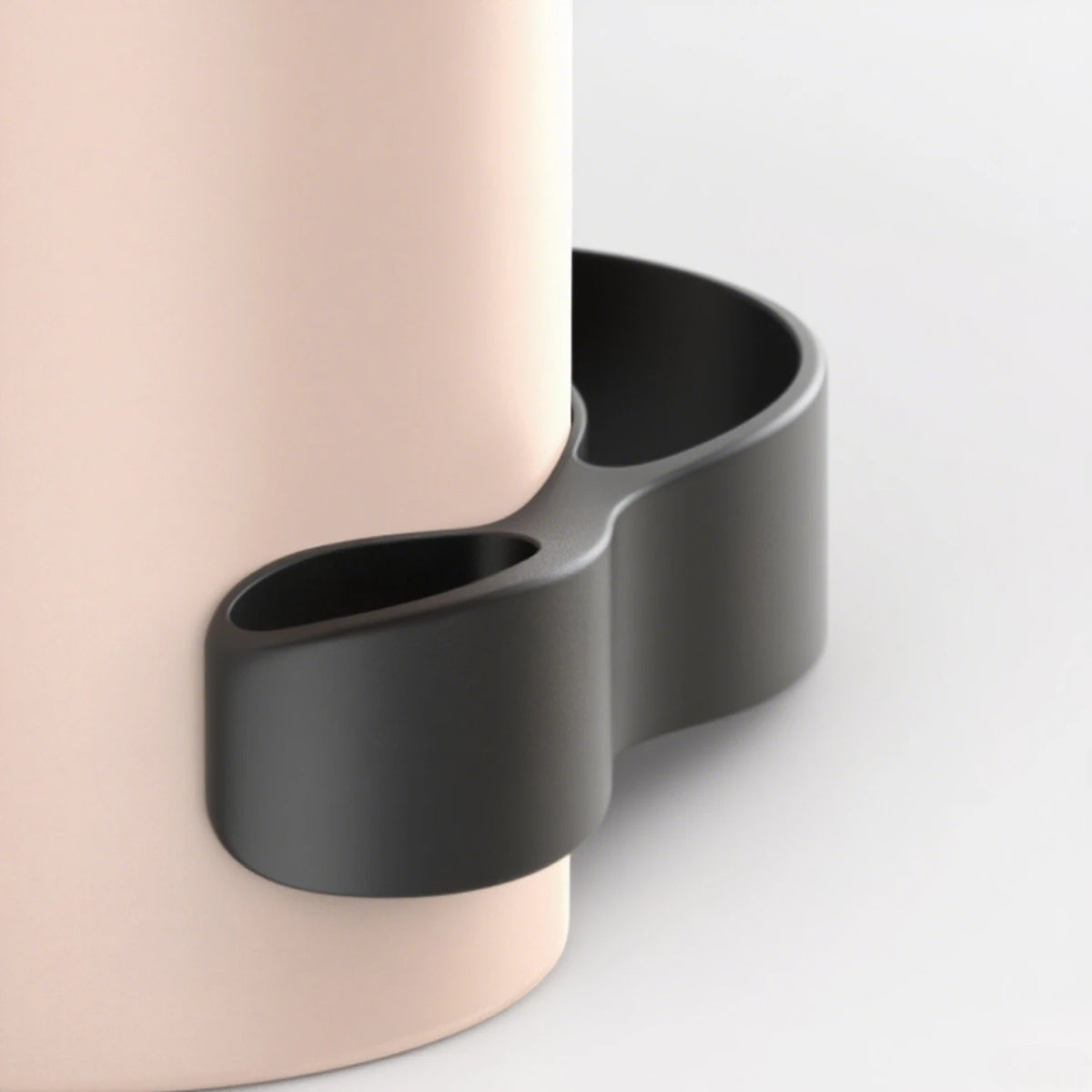 A black silicone cable organizer is shown next to a light pink cylindrical object.