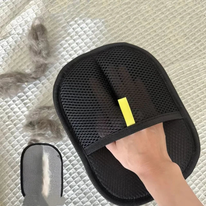 A hand is using a black pet hair removal glove for cats and dogs on a light textured surface.