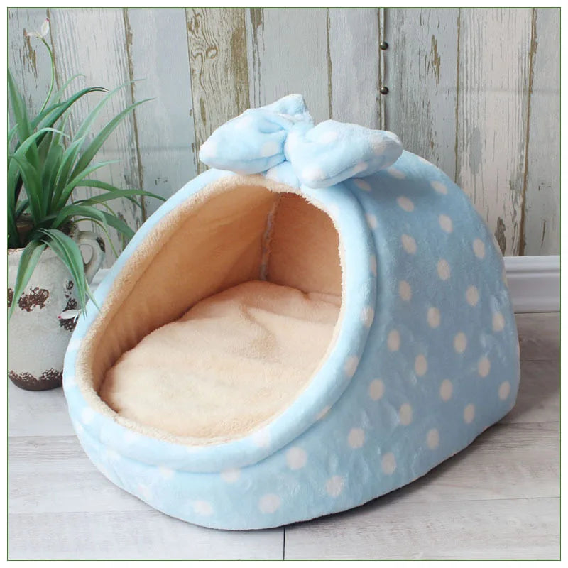 A light blue, polka-dotted pet bed with a soft interior lining is shown on a wooden floor.