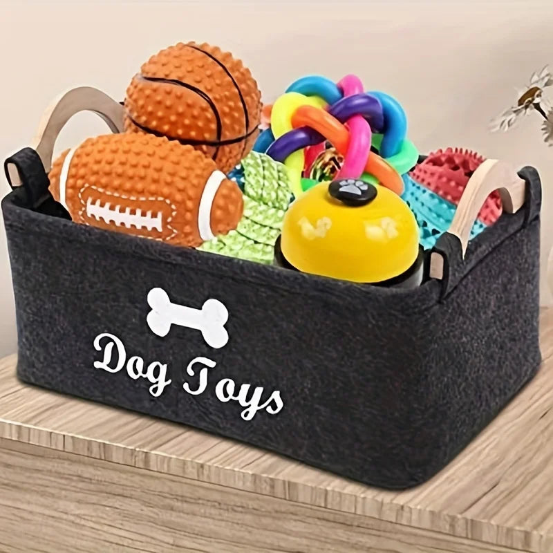 Panier de rangement noir rempli de jouets pour chiens en feutre, y compris une balle, un os et des jouets à mâcher colorés.