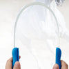 A hand holds an expandable dual-sided grooming comb with a curved, clear plastic blade for pets.