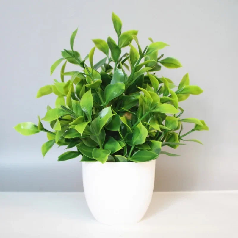 A vibrant green artificial bonsai plant in a white pot displayed on a light surface.