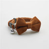A brown plush velvet pet collar featuring a bow and a silver bell.