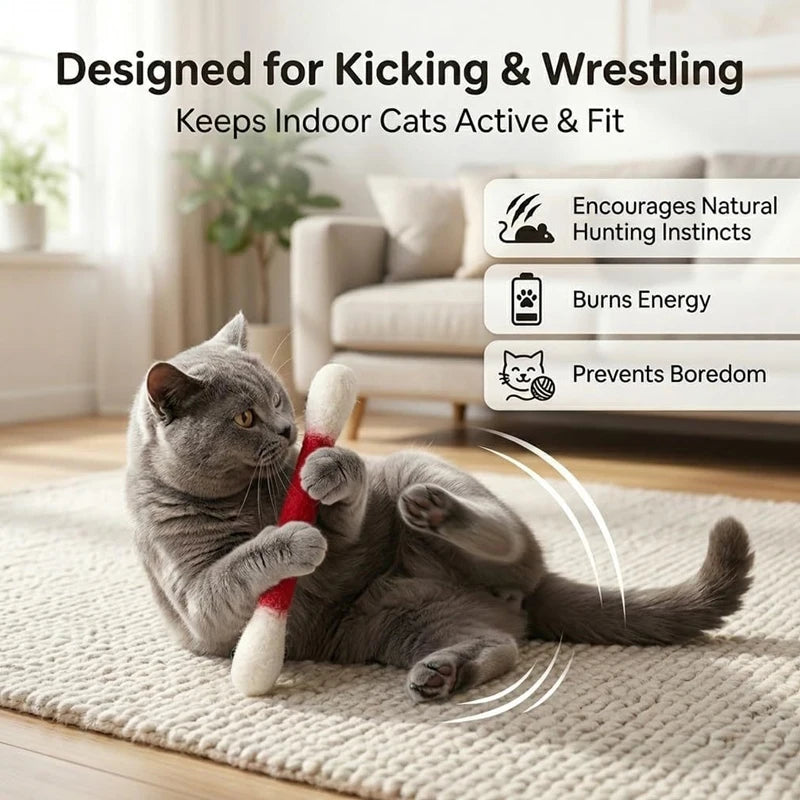 A gray cat is playing with a red felt chew stick on a light-colored rug.