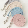 A stack of beige, gray, and blue pet leash harnesses coiled together.