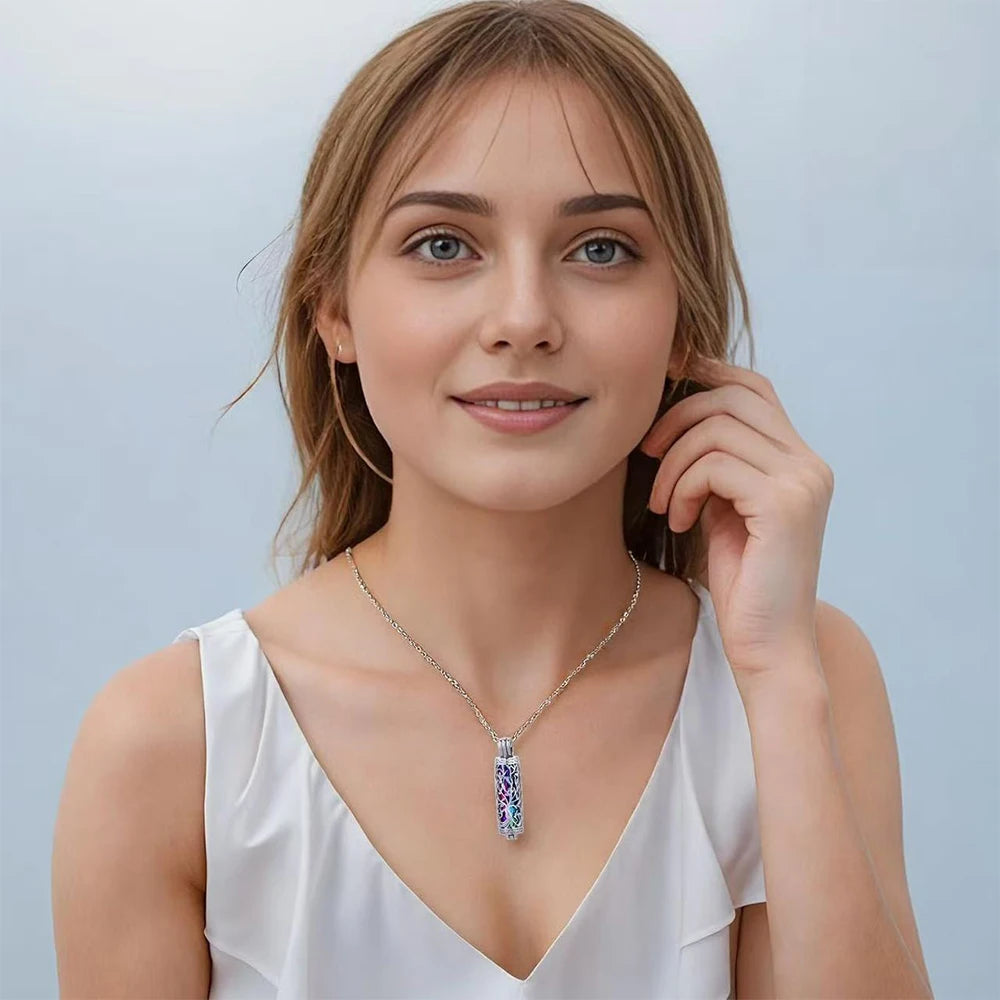 A young woman models a silver cylinder cremation urn necklace with blue and purple stones.