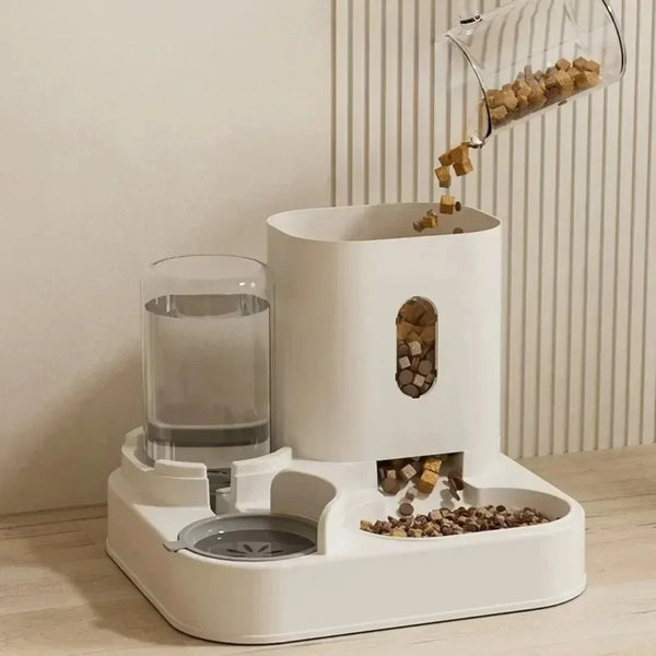 A white gravity-fed pet food and water station with a glass dispenser pouring kibble into a bowl.